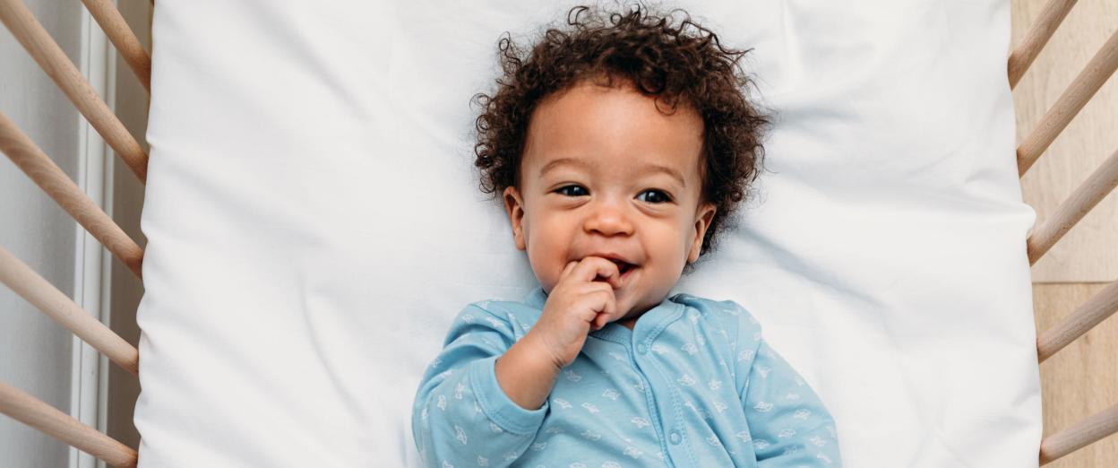 18 month old baby laying in crib wearing blue pajamas