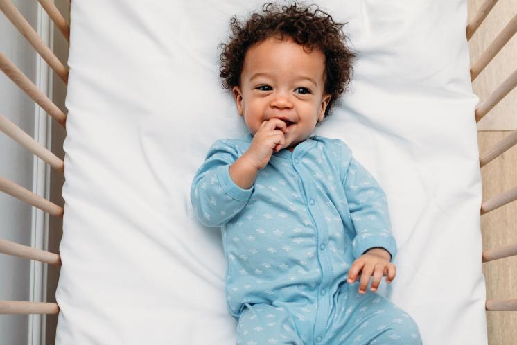 18 month old baby laying in crib wearing blue pajamas