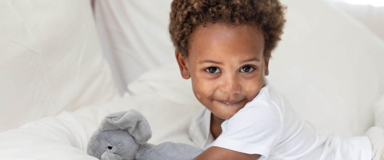 3 year old laying in bed smiling