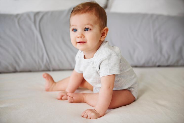 seven month old sitting up looking away from camera
