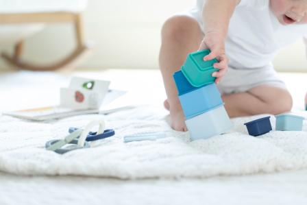baby sitting playing by stacking square silicone containers