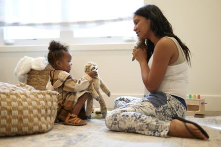 Mom and toddler playing together happily with stuffed animals