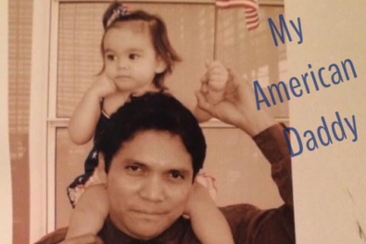dad holding toddler on shoulders with an American flag in hand