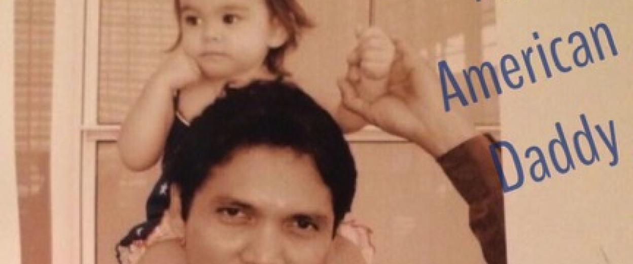 dad holding toddler on shoulders with an American flag in hand