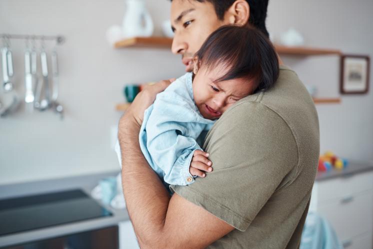 dad holding crying baby on his shoulder, trying to help him go to sleep