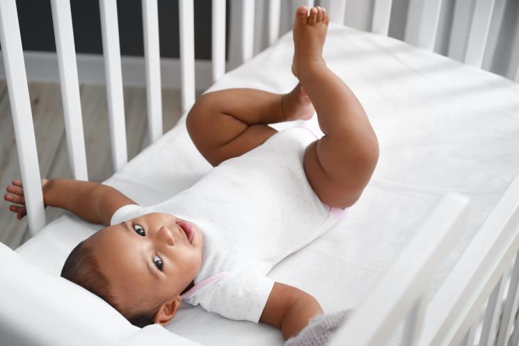 Baby laying in crib with arms extended