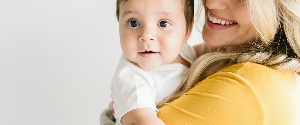 Mom looking at baby in her arms and baby looking away as they prepare for babysitter