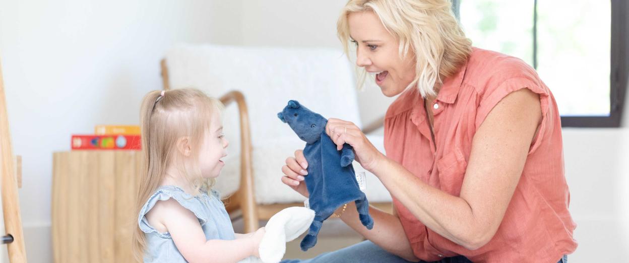 woman and child sitting smiling and holding loveys