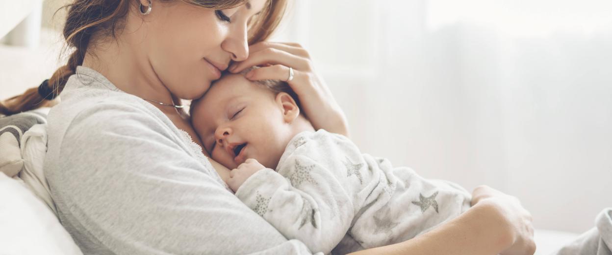 Mom with baby on chest smiling with eyes closed