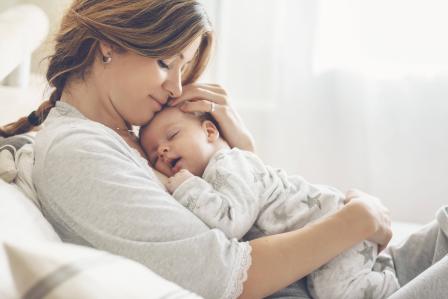 Mom with baby on chest smiling with eyes closed