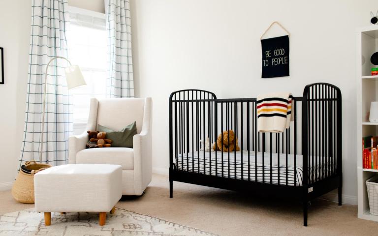 modern decorated nursery with lamp, glider, black crib