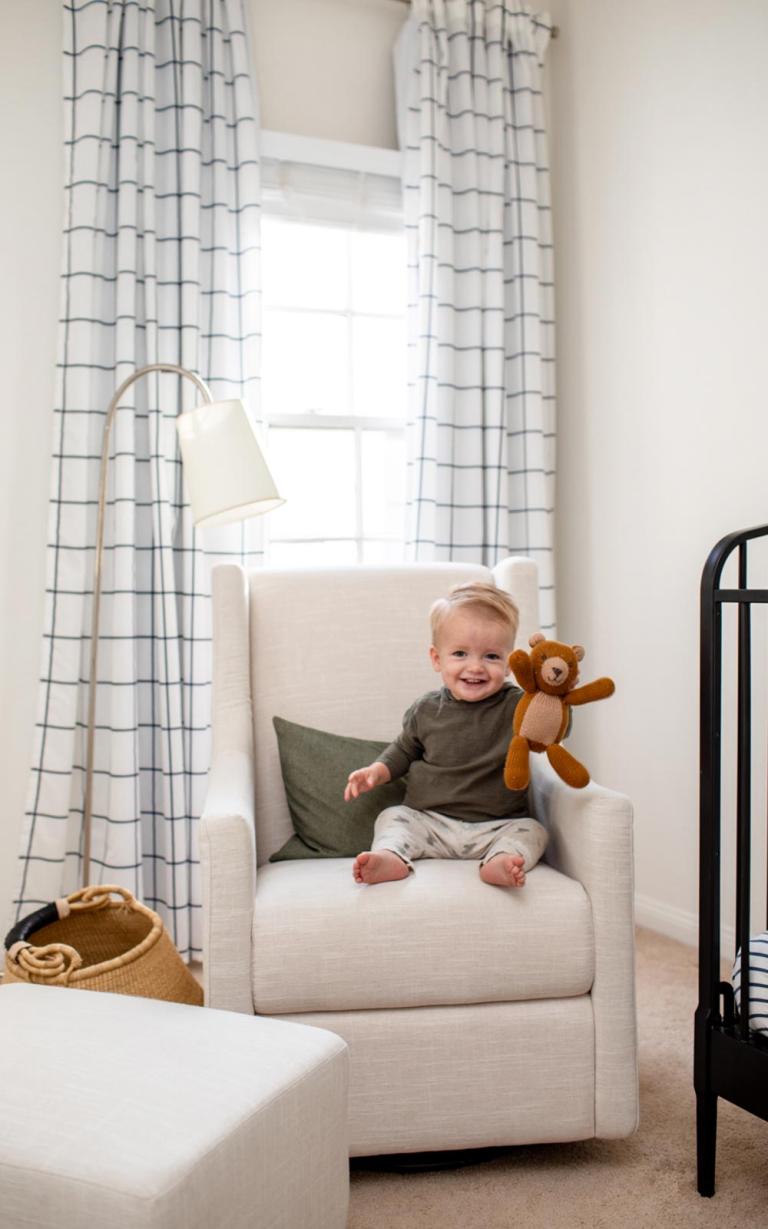 toddler in nursery sitting on rocker with stuffed bear