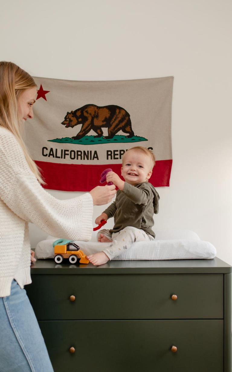 happy toddler on changing table playing with mom