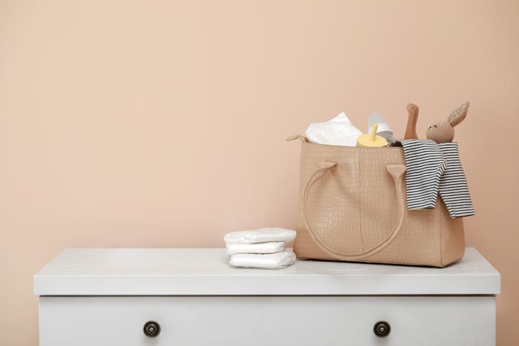 diaper bag ready to be reloaded sitting on dresser against a tan background