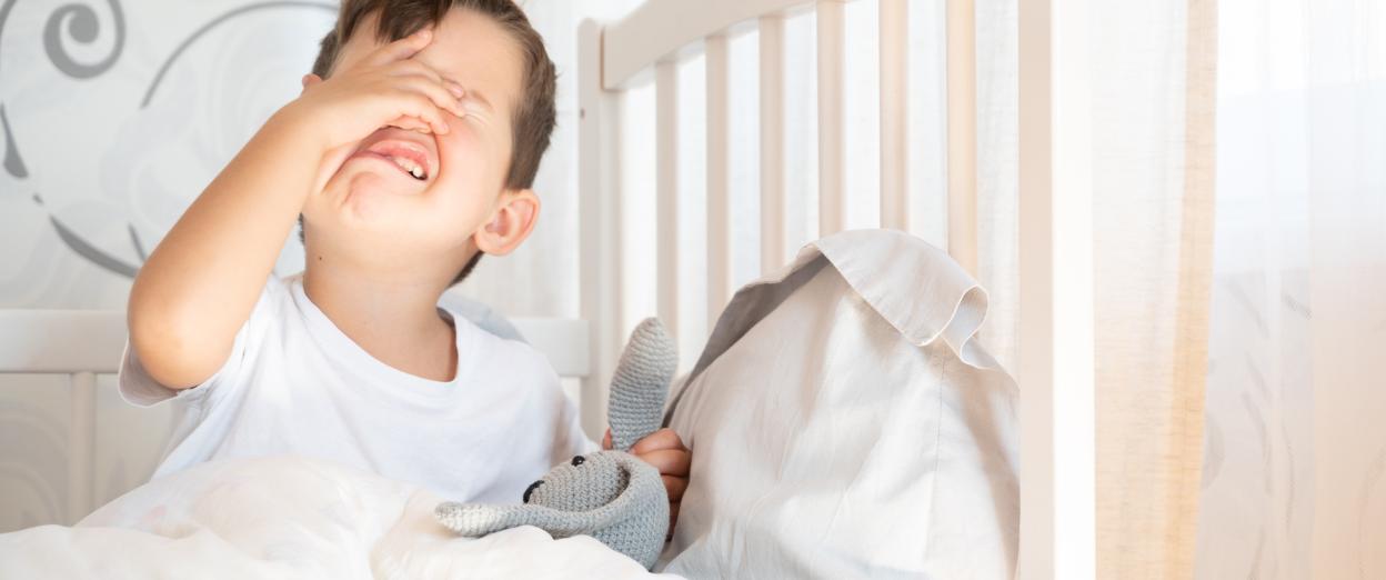 toddler boy in bed protesting bedtime