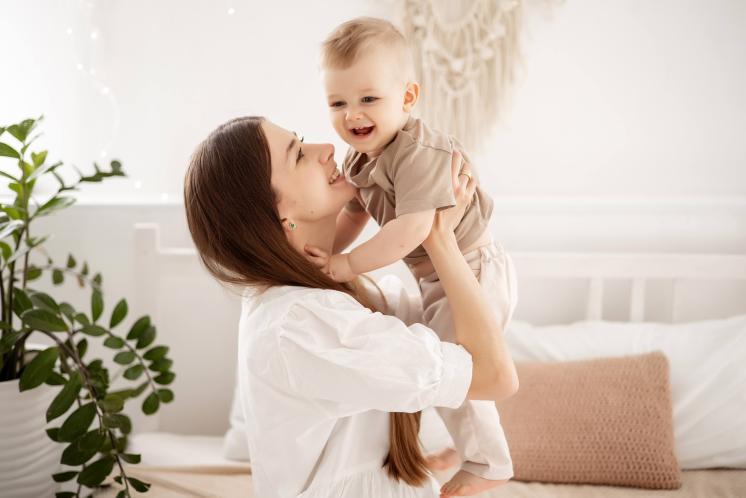 mom holding baby up above her and gazing at baby smiling
