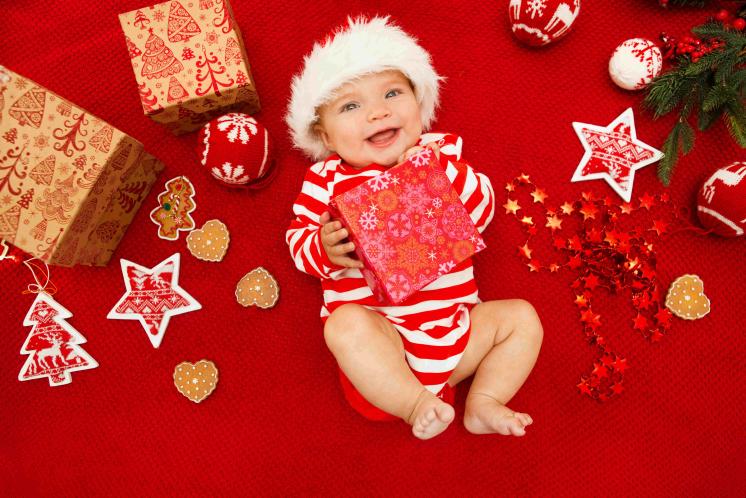 baby wearing santa hat and holding christmas present