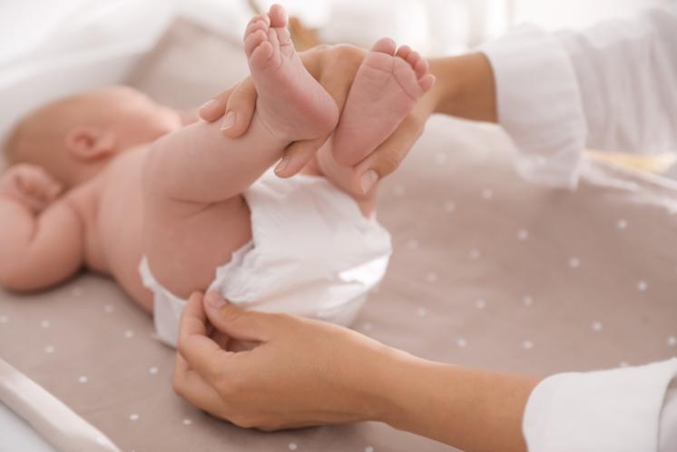view of young baby on changing table about to get their diaper changed, focus on feet no view of face