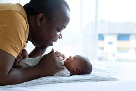 father having face to face time with newborn baby laying on a white blanket