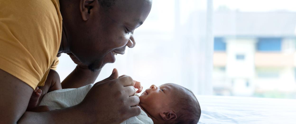 father having face to face time with newborn baby laying on a white blanket