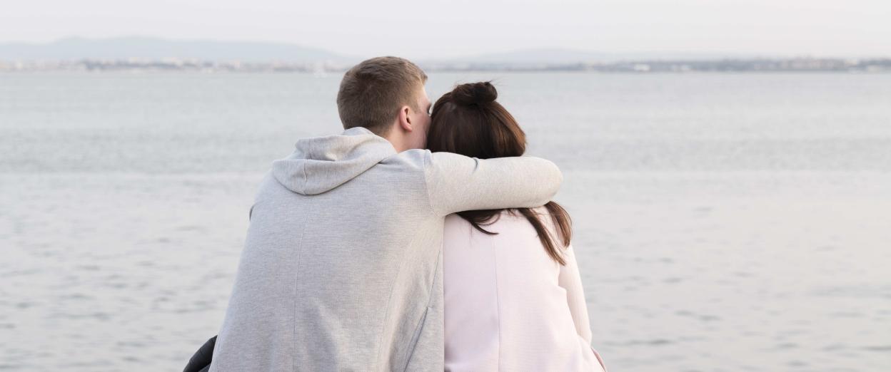 man giving a woman an caring hug facing away from the camera