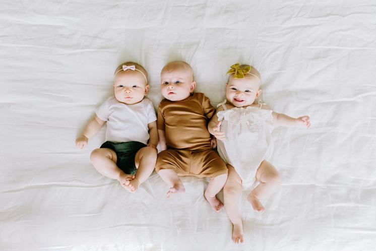 three three month old babies actively looking around and smiling at the camera