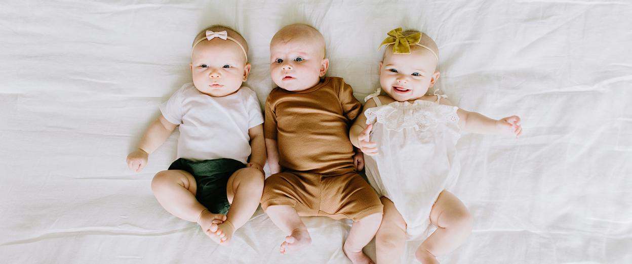 three three month old babies actively looking around and smiling at the camera