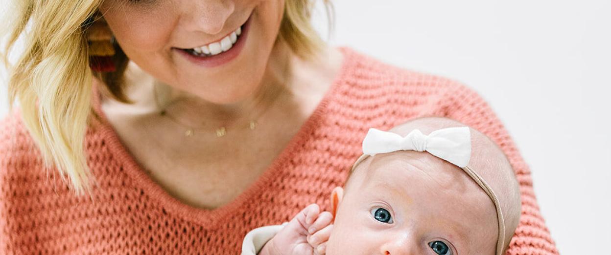 Cara holding newborn baby looking down at her