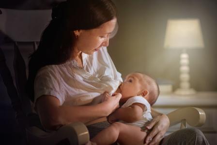 mom in rocking chair nursing baby in the dark