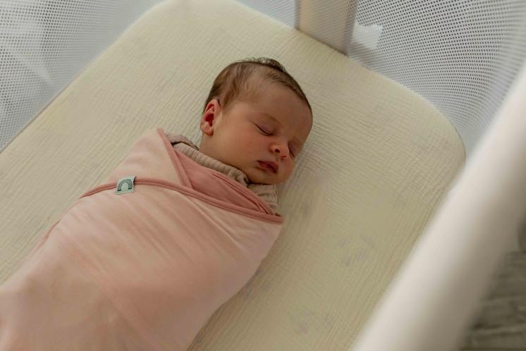 swaddled newborn asleep in crib