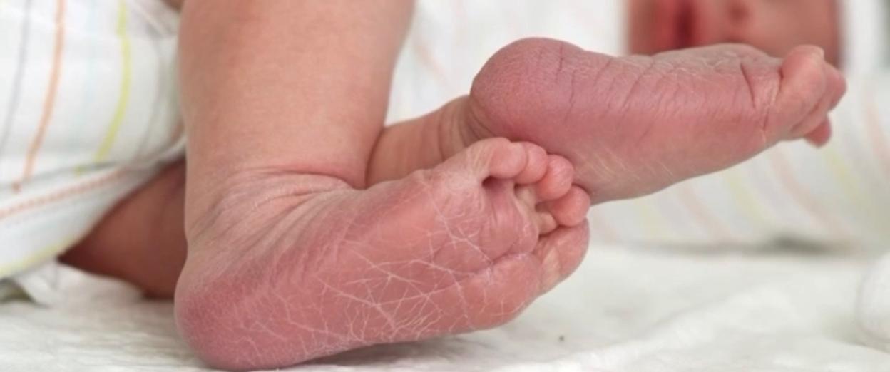 unclose view of newborn baby feet with baby curled to the side