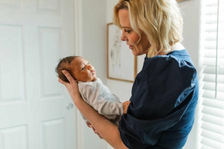 newborn baby staring away as a sleepy cue while being held by Cara