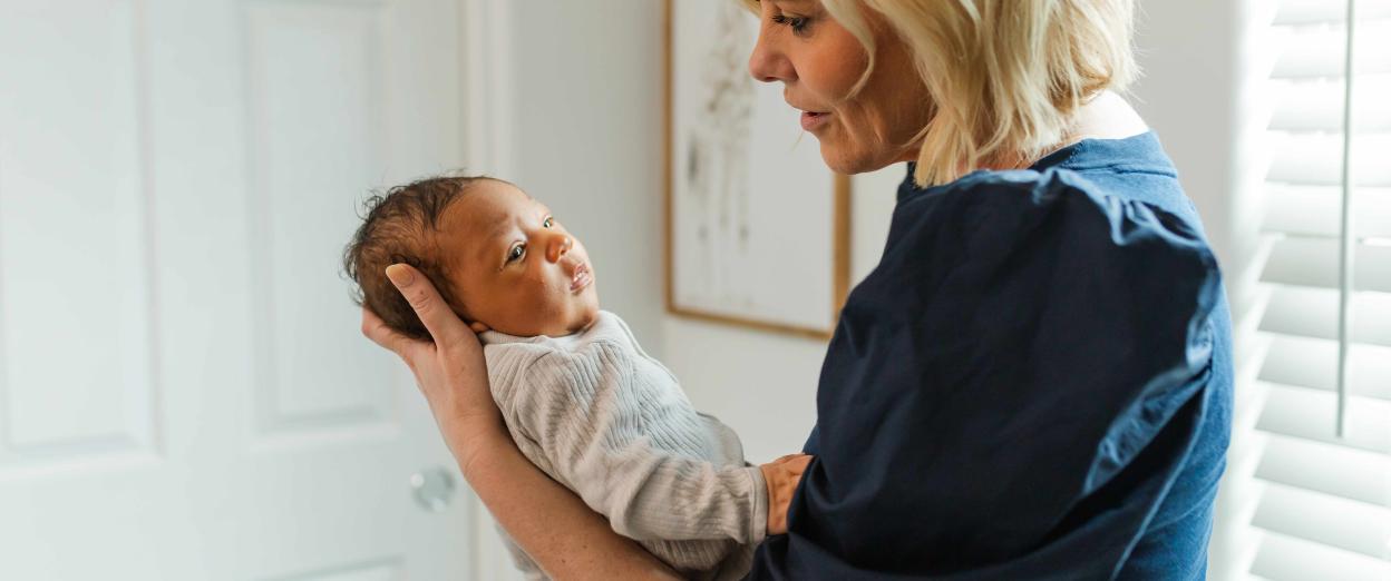 newborn baby staring away as a sleepy cue while being held by Cara