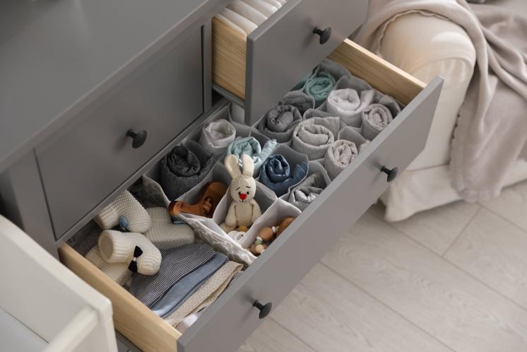 open dresser drawer filled with baby clothes, toys, and accessories neatly organized