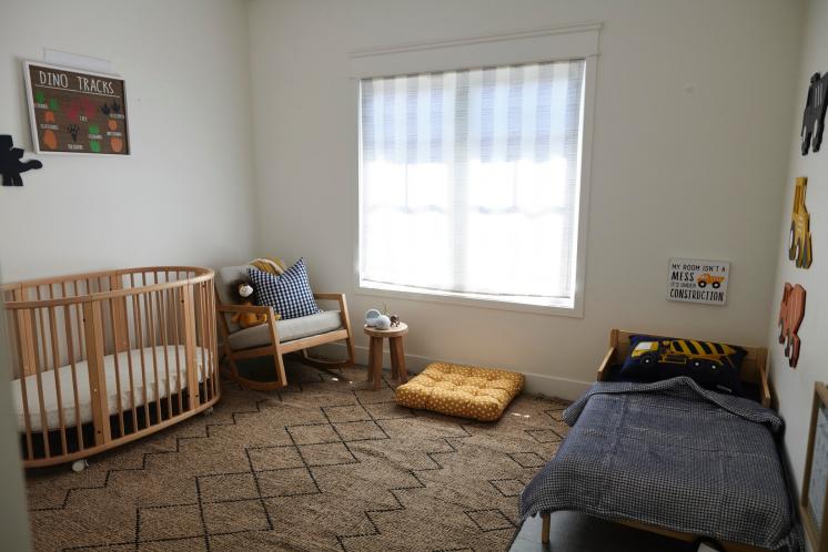 young boys bedroom with crib on one side of the room and a toddler bed on the other side