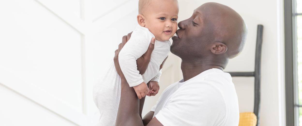 Dad kissing baby on the cheek after getting him out of crib in the morning