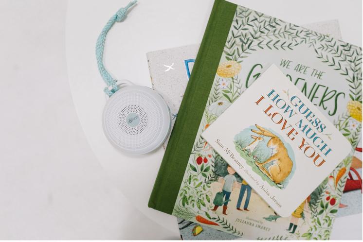 Portable sound machine laying on white table next to children's books in nursery