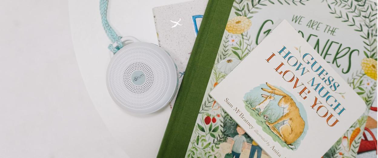 Portable sound machine laying on white table next to children's books in nursery