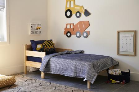 toddler bed with navy blue bedding and construction vehicle decorations around the room