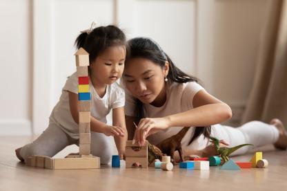 Toddler girl playing blocks on the floor with mom