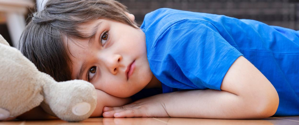 tired toddler gazing into the distance while laying on the floor refusing to nap