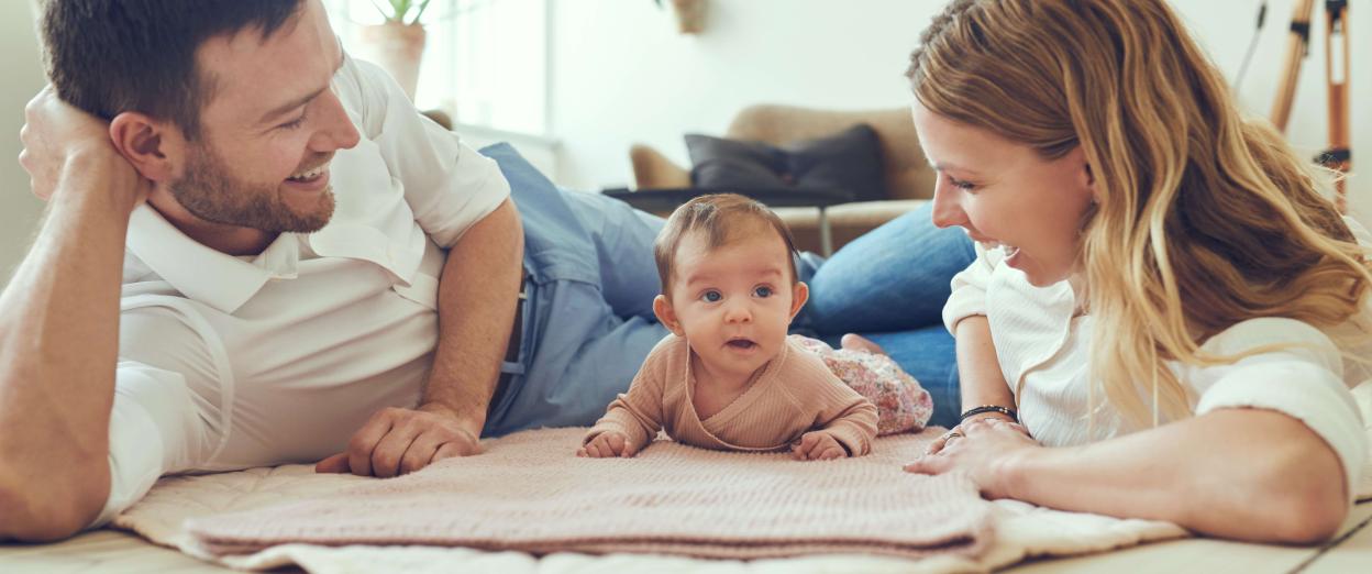 Mom and Dad laying on mat with baby doing tummy time