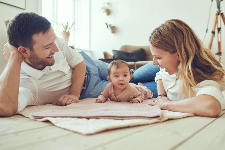 Mom and Dad laying on mat with baby doing tummy time