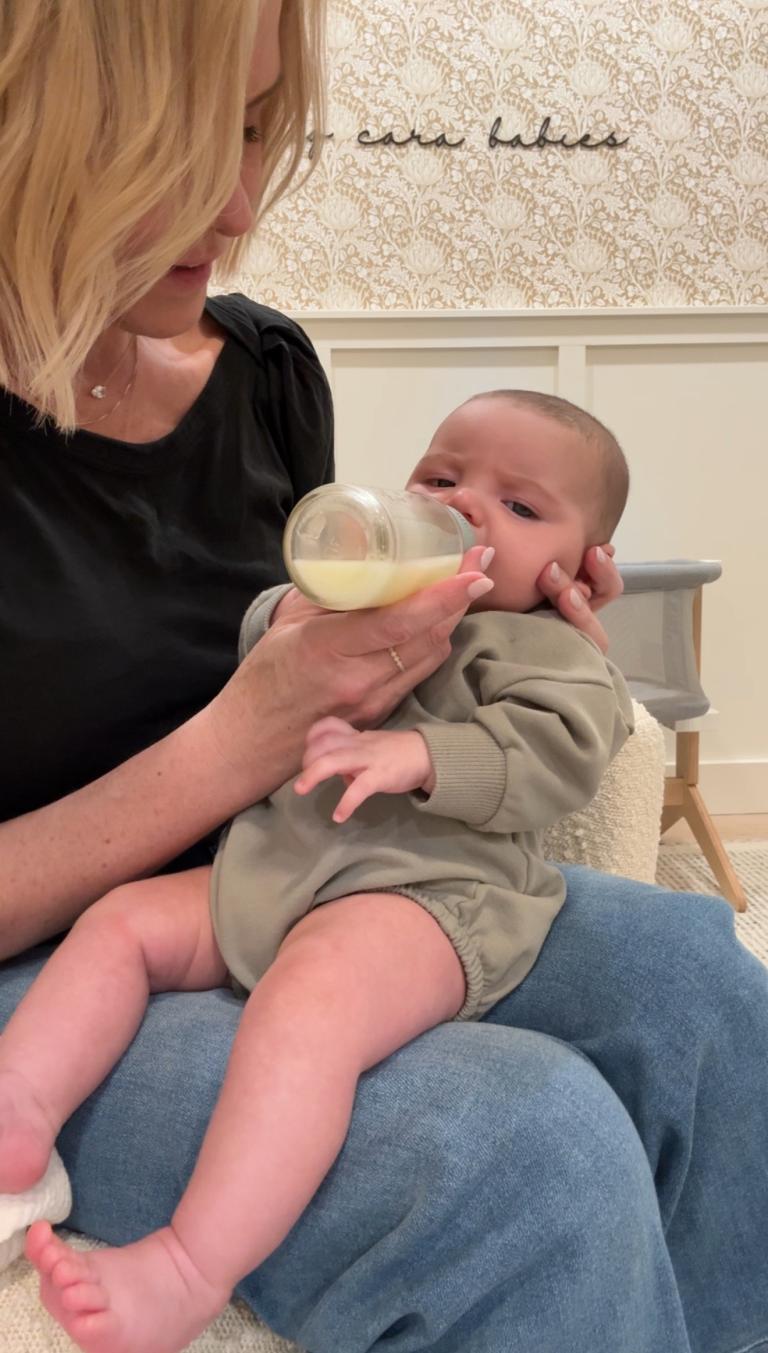 baby being held seated upright and offered a bottle