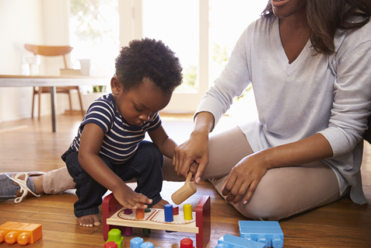 19 month old squatting down to play with peg toy with his mom on the floor